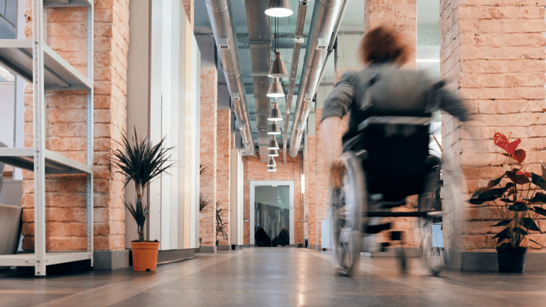 Une femme se déplace en fauteuil roulant dans un édifice.